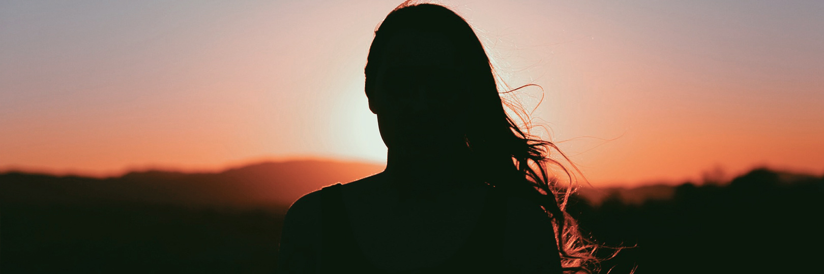 Frau schaut in den Sonnenuntergang